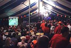 Voetbalwedstrijd via videoschermen in de feesttent.